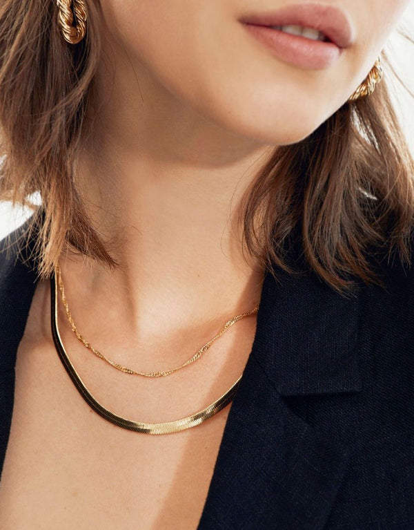 Set of 2 layered charm necklaces on a woman's neck.