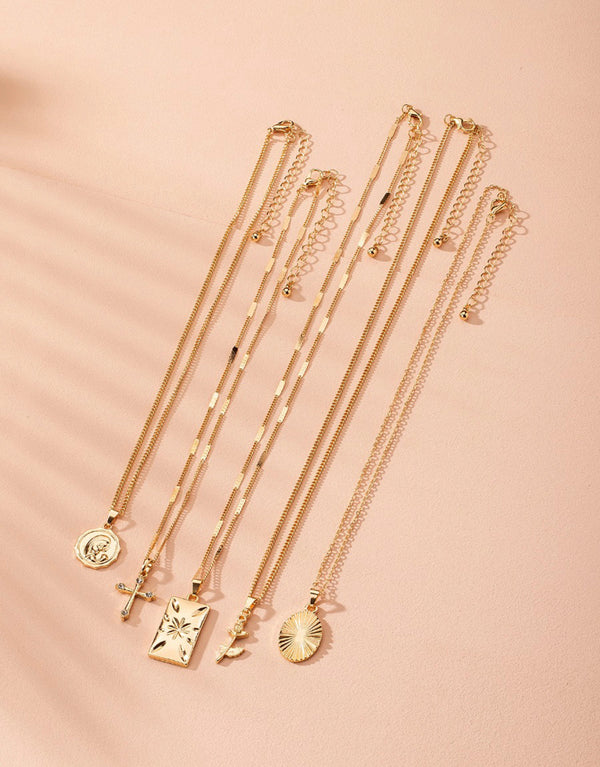 Set of 5 charm necklaces in gold tones, Layered necklaces with cross, oval, coin, square, and rose charms, Adjustable extension chain for a perfect fit.
