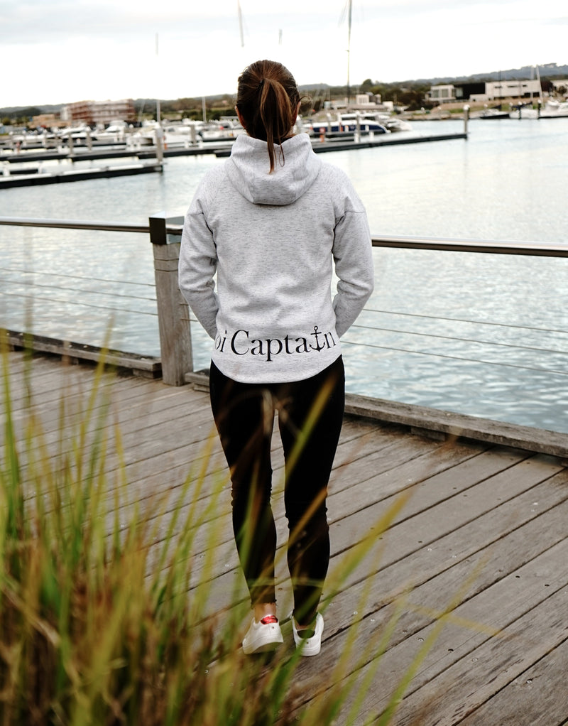 Elevate your casual weekend collection with the Carpe Diem Soft Essentials Hoodie. For all day comfort, this will be your go to.  Features trendy curved back, comfortable cotton bonded polar fleece lined hoodie jacket, drop shoulders add to this relaxed fit, and classic finishing touches, like zipped side pockets and piped trimmed edging. Quality vinyl heat pressed Oi Captain logo on front chest and lower back, and Licinia the label coastal collection set 2021 type graphic on sleeve.